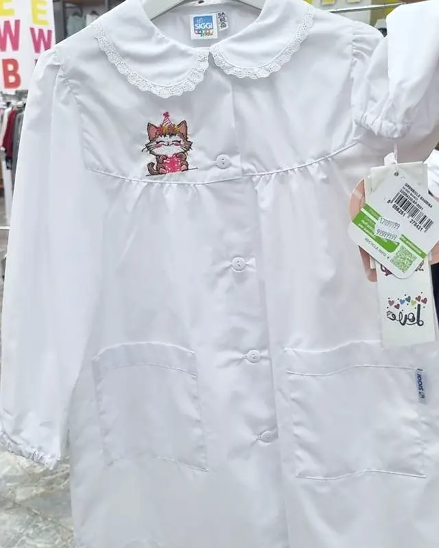 Grembiule bianco da asilo con colletto in pizzo, due tasche e ricamo di un gattino con il regalo