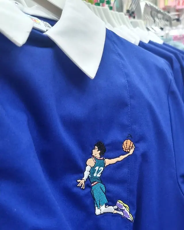 Grembiule blu da scuola primaria con colletto bianco e ricamo di un giocatore di basket