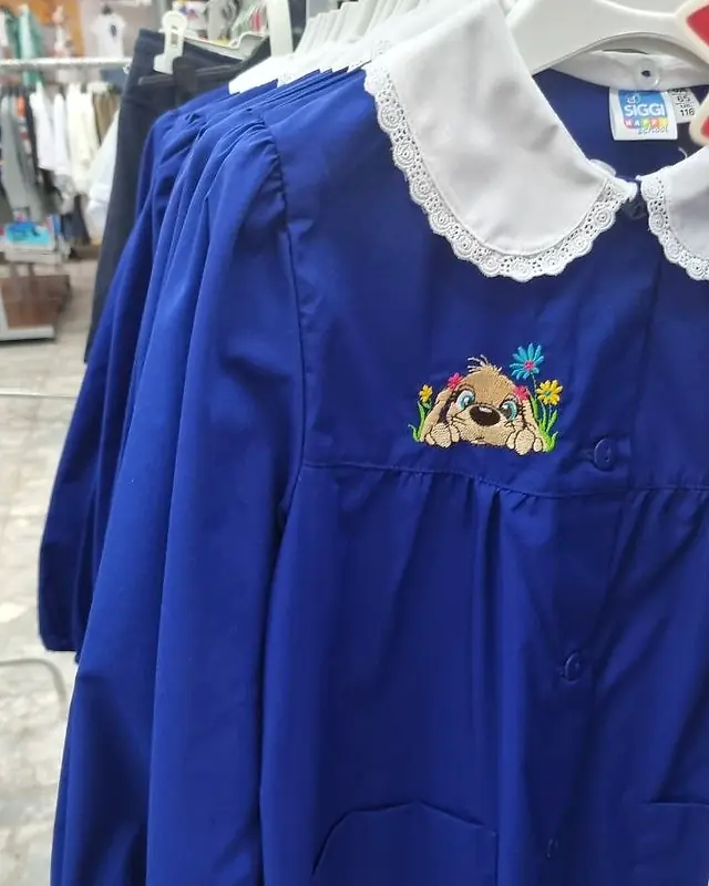 Grembiule blu da scuola primaria con colletto bianco in pizzo e ricamo di un cagnolino tra i fiori