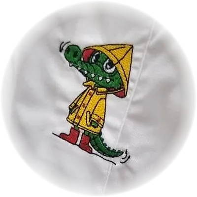 Ricamo di un coccodrillo con impermeabile e cappello giallo, su grembiule bianco