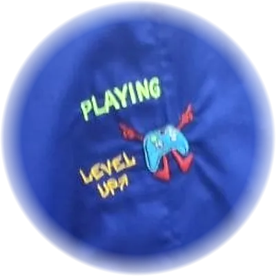 Ricamo di un joystick con la scritta Playing Level Up, su grembiule blu