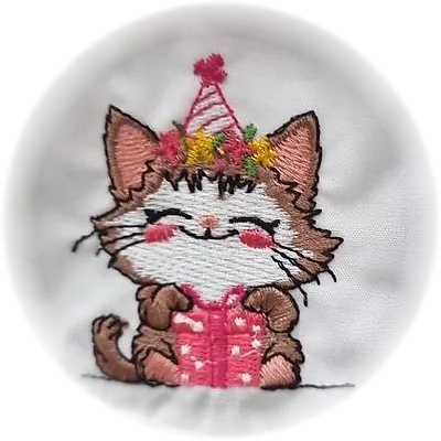 Ricamo di un gattino con cappellino di festa e regalo, su grembiule bianco